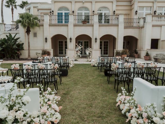 An outdoor wedding setup with chairs, flowers, and decorations in front of a large building.