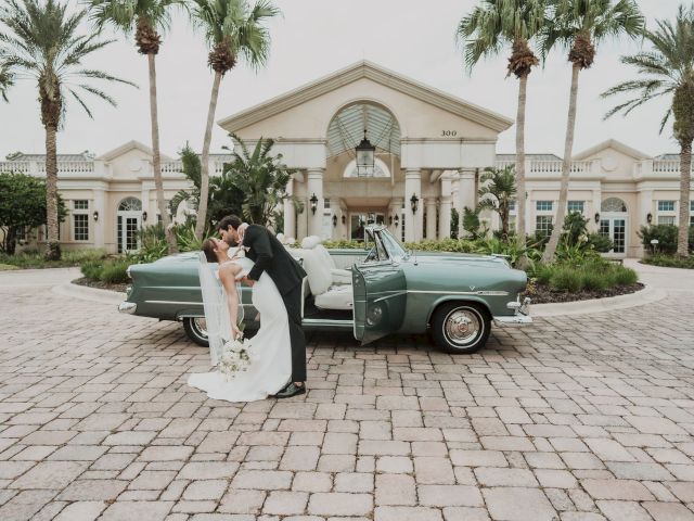 A couple kisses by a vintage car in front of a grand building with palm trees, creating a romantic and elegant scene.