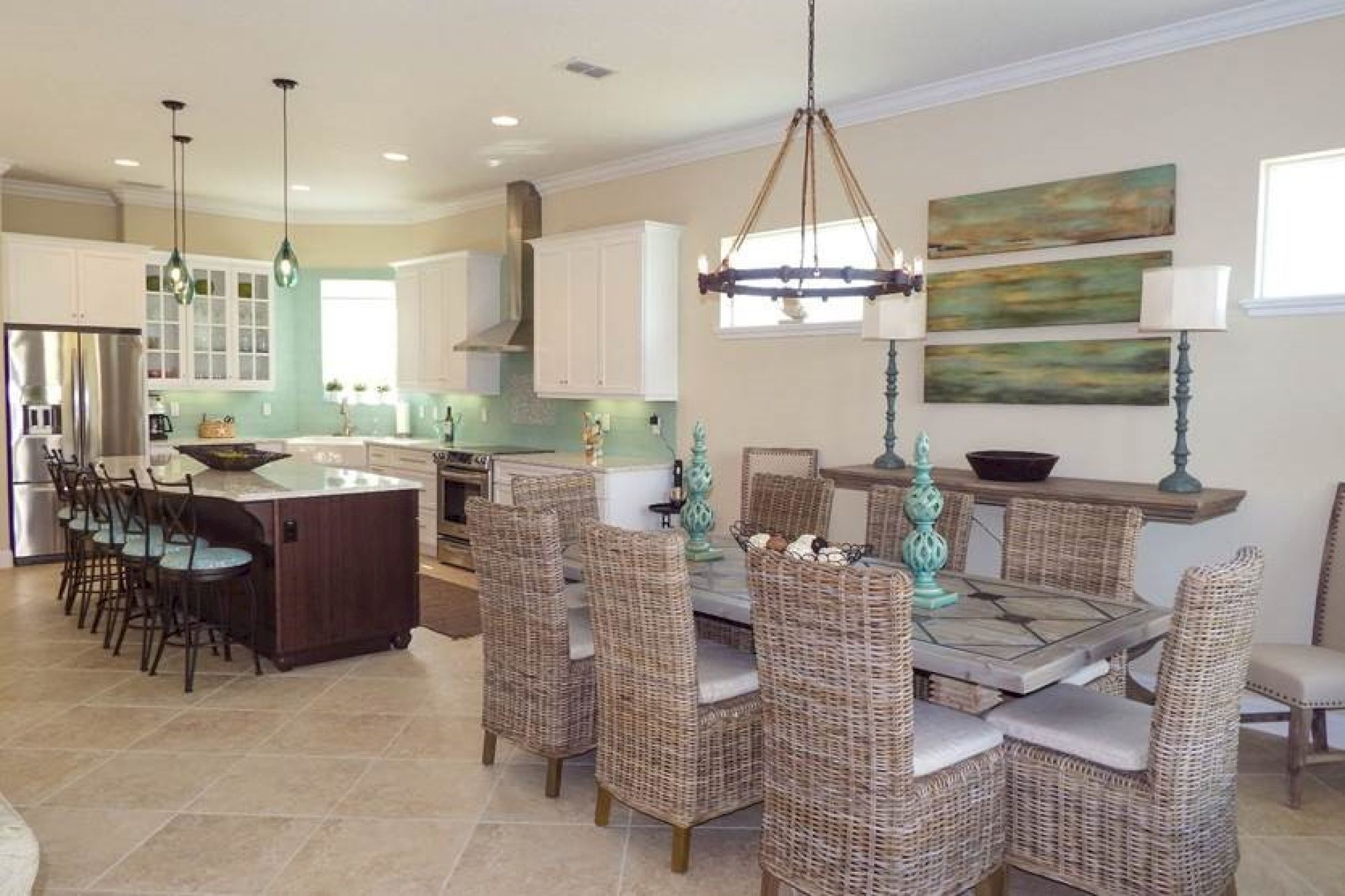 A spacious kitchen and dining area with wicker chairs, a modern island, hanging lights, and decorative accents for a cozy, elegant atmosphere.
